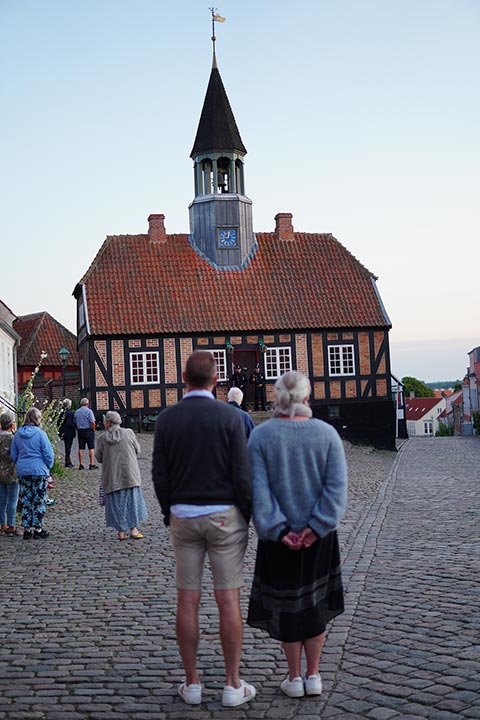Turister kigger mod Vægterne foran det gamle rådhus i Ebeltoft, der gør klar til at gå vægtergang i byen